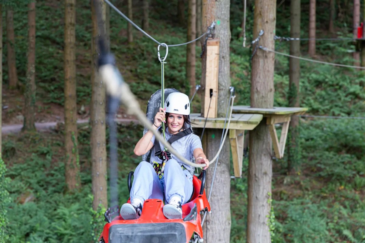 a young girl navigates a high ropes course in the woods. Things to do with teenagers in North Wales.