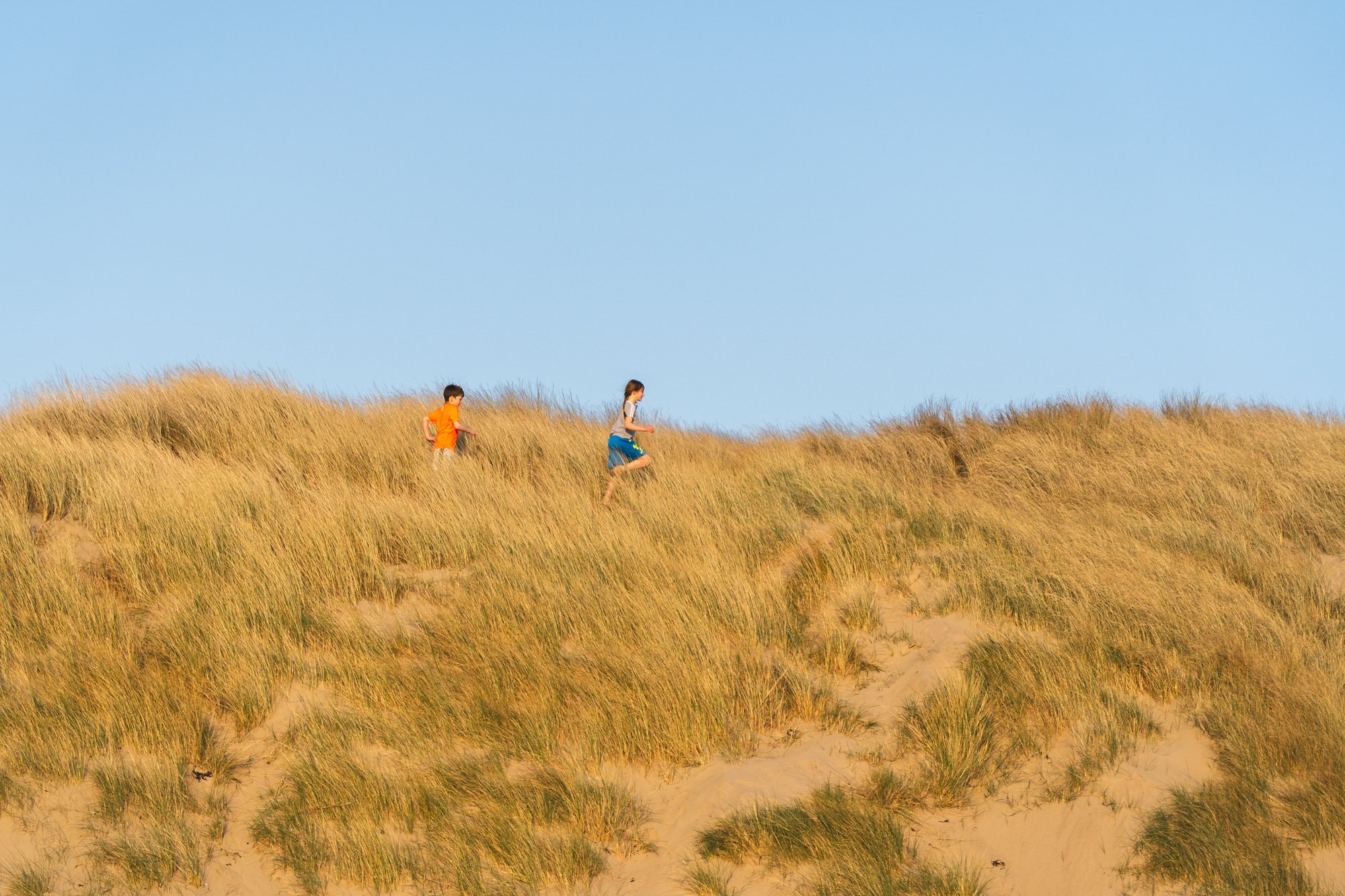 Children running in beach dunes on a last minute break in north wales