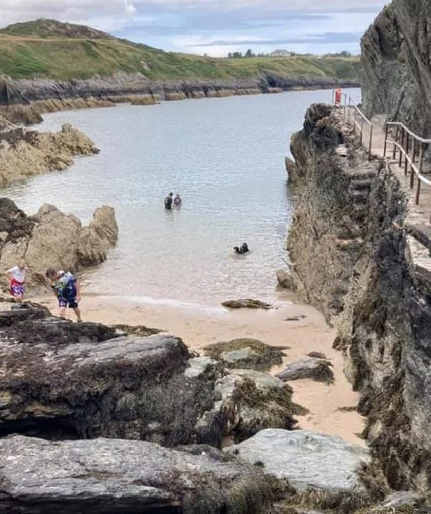The small tidal beach at Porth Dynion pictured with people in the water and on the sand