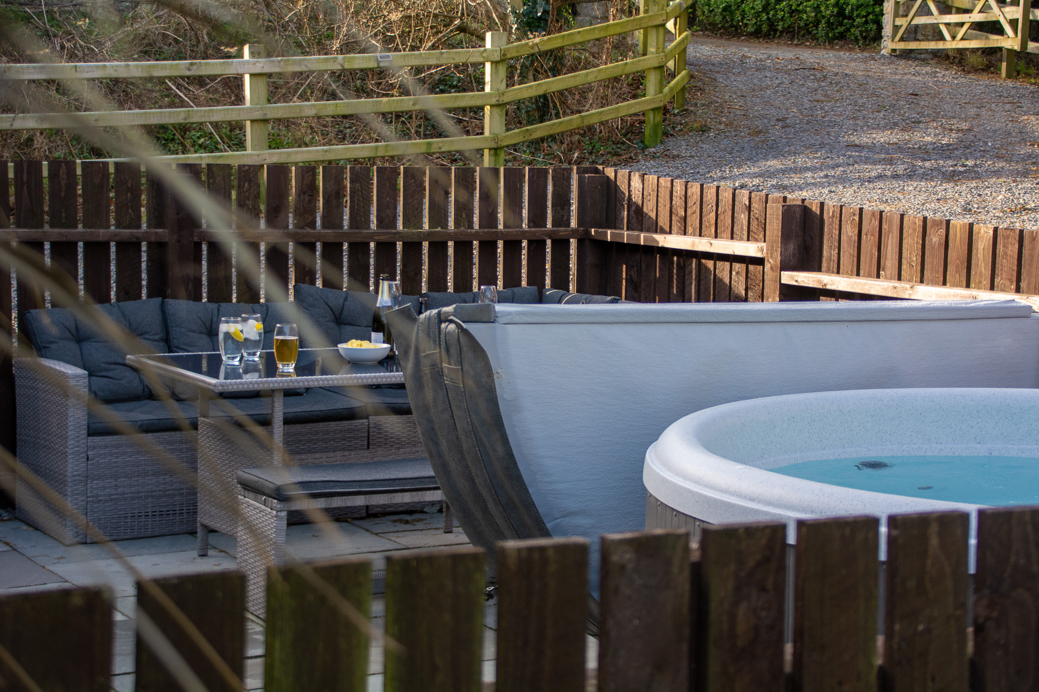 Exterior shot of hot tub and outdoor furniture with drinks at Y Caban in Cemaes Bay, Anglesey.