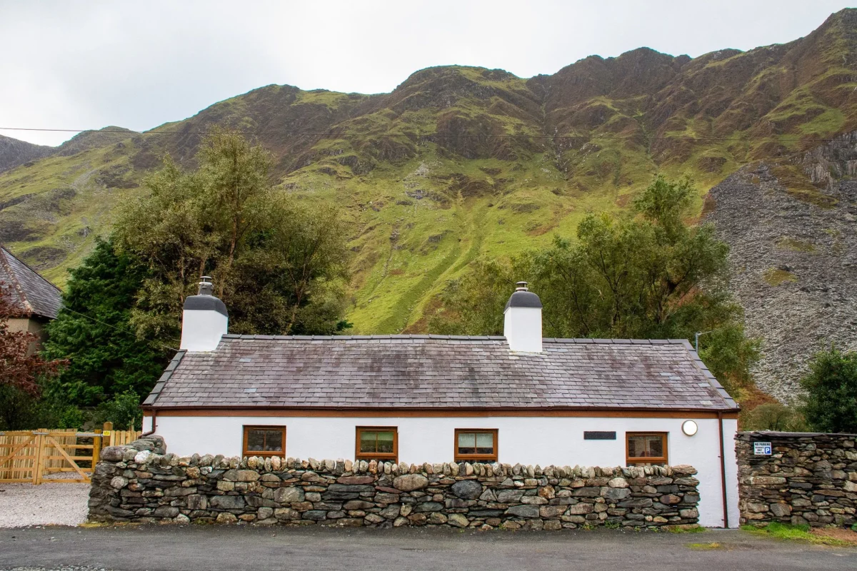 An idyllic white stone cottage in Snowdonia with mountain scenery behind
