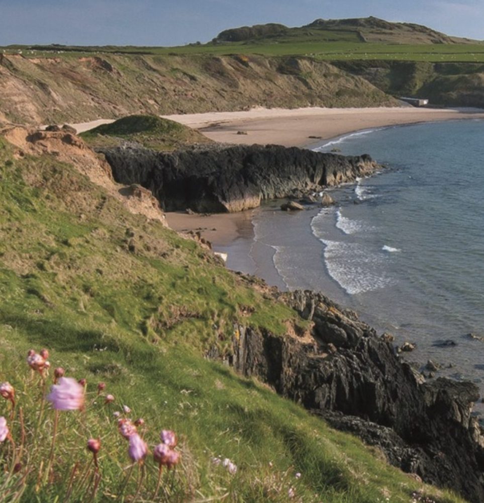 Porthor (Whistling Sands) beach on the northern Llyn Peninsula, a sheltered sandy cove with crystal-clear water and coastal path views