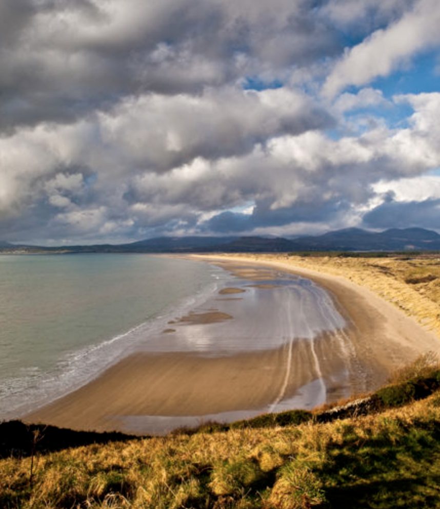 Harlech Beach backed by sand dunes with the Snowdonia mountains visible in the distance, North Wales
