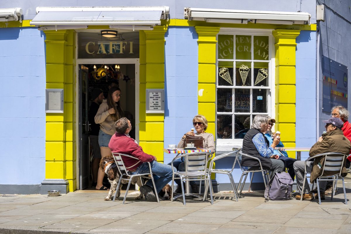 An image of diners sitting outside a colourful Caernarfon cafe in the sunshine