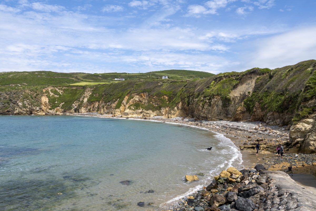 The curving headland and rocky beach of Church Bay at high tide, Anglesey 