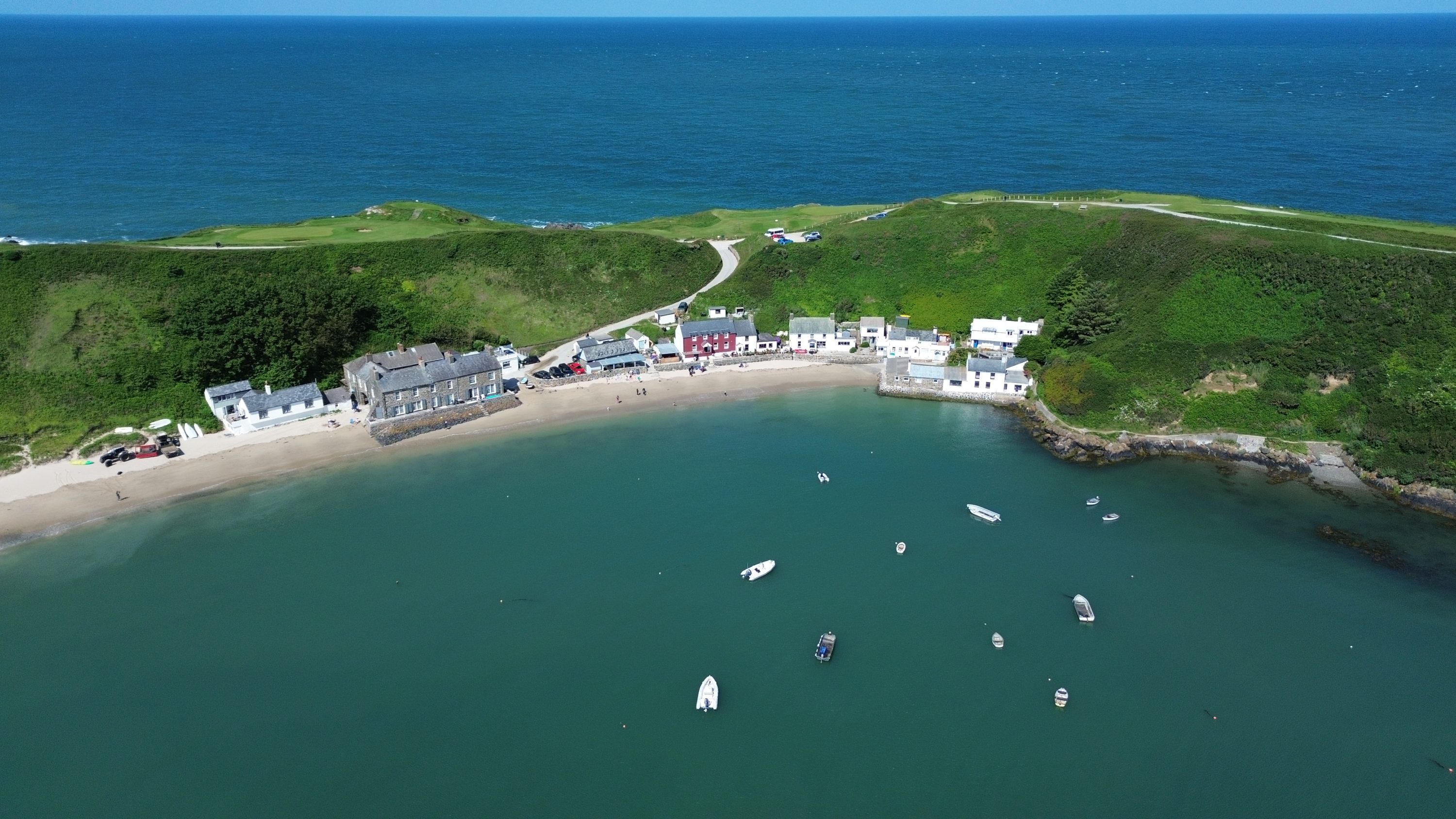 Aerial shot of Porthdinllaen, Morfa Nefyn, North Wales, featuring turquoise sea, white sandy beach and waterfront houses as well as Ty Coch pub.