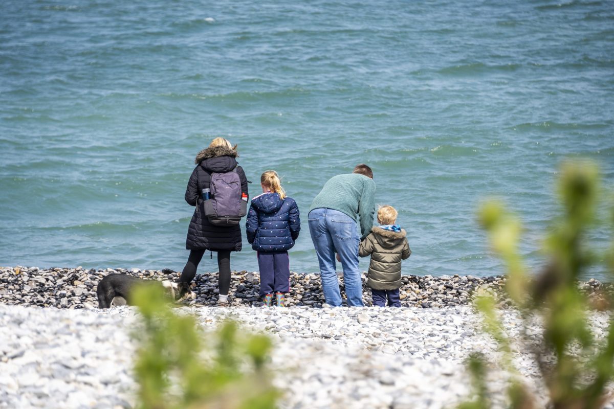 A family of four standing on a shingle beach