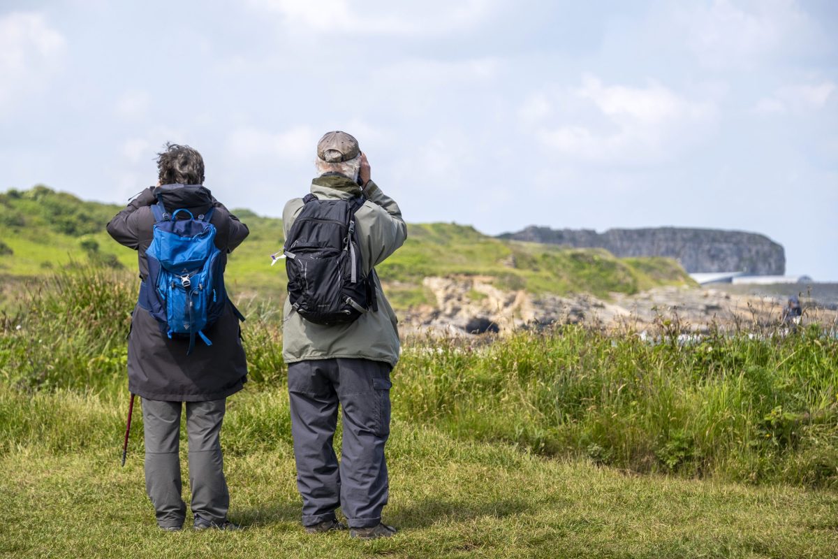 Two walkers on the Anglesey Coast Path stopping to look for birds and other wildlife 