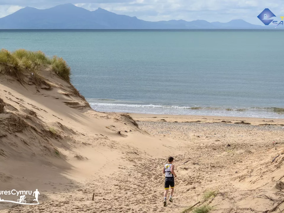 A lone participant running along the sand at Newborough Beach, Anglesey