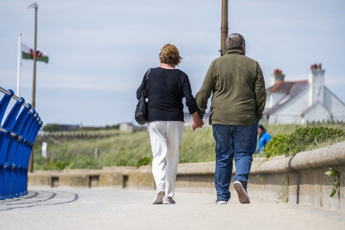 Two people holding hands as they walk a section of the Anglesey coast path 
