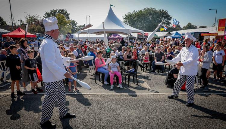 Two men dressed as chefs entertaining a crowd at Mold Food Festival