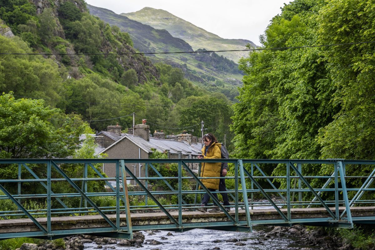 A couple crossing a metal bridge in the village of Beddgelert, north wales.