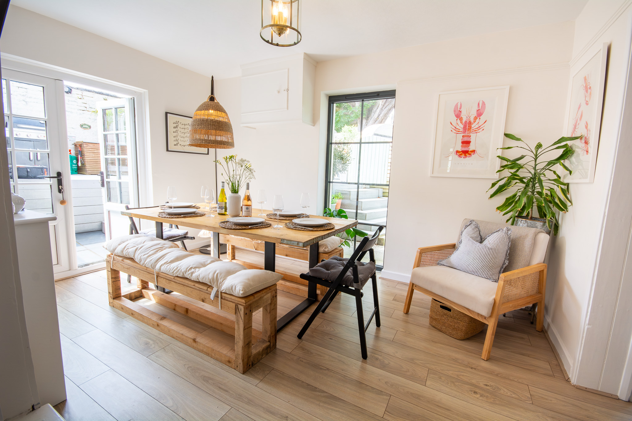 Contemporary dining room with modern decor on a dressed dining table, plants and prints on the wall.