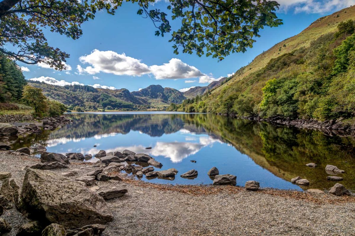 A view across Llyn Crafnant in North Wales with blue skies and a perfect reflection atop the water.