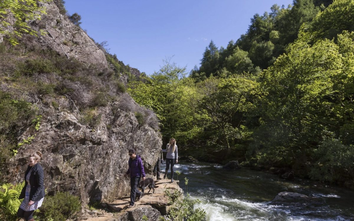 Three people walking along the gorge at the aberglaslyn pass